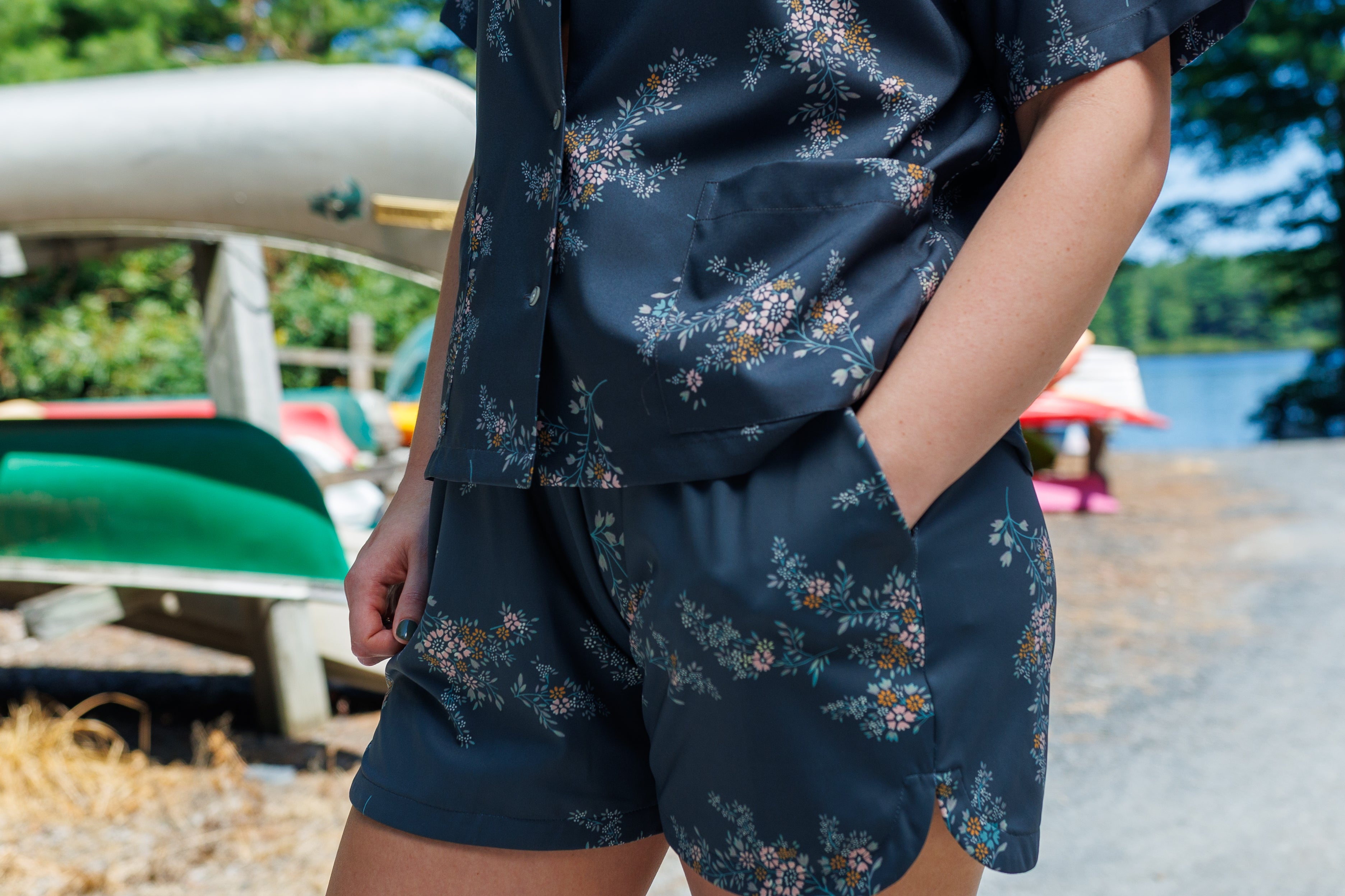 Floral shirt and shorts set displayed in a forested boatyard.