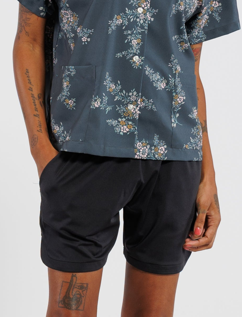 Person wearing a floral shirt and black shorts on a white background