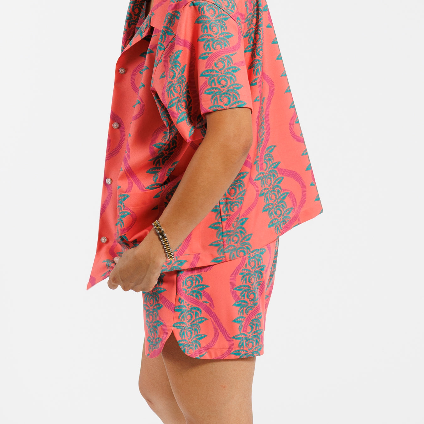 Person wearing a pink and green leaf patterned outfit on a white background.