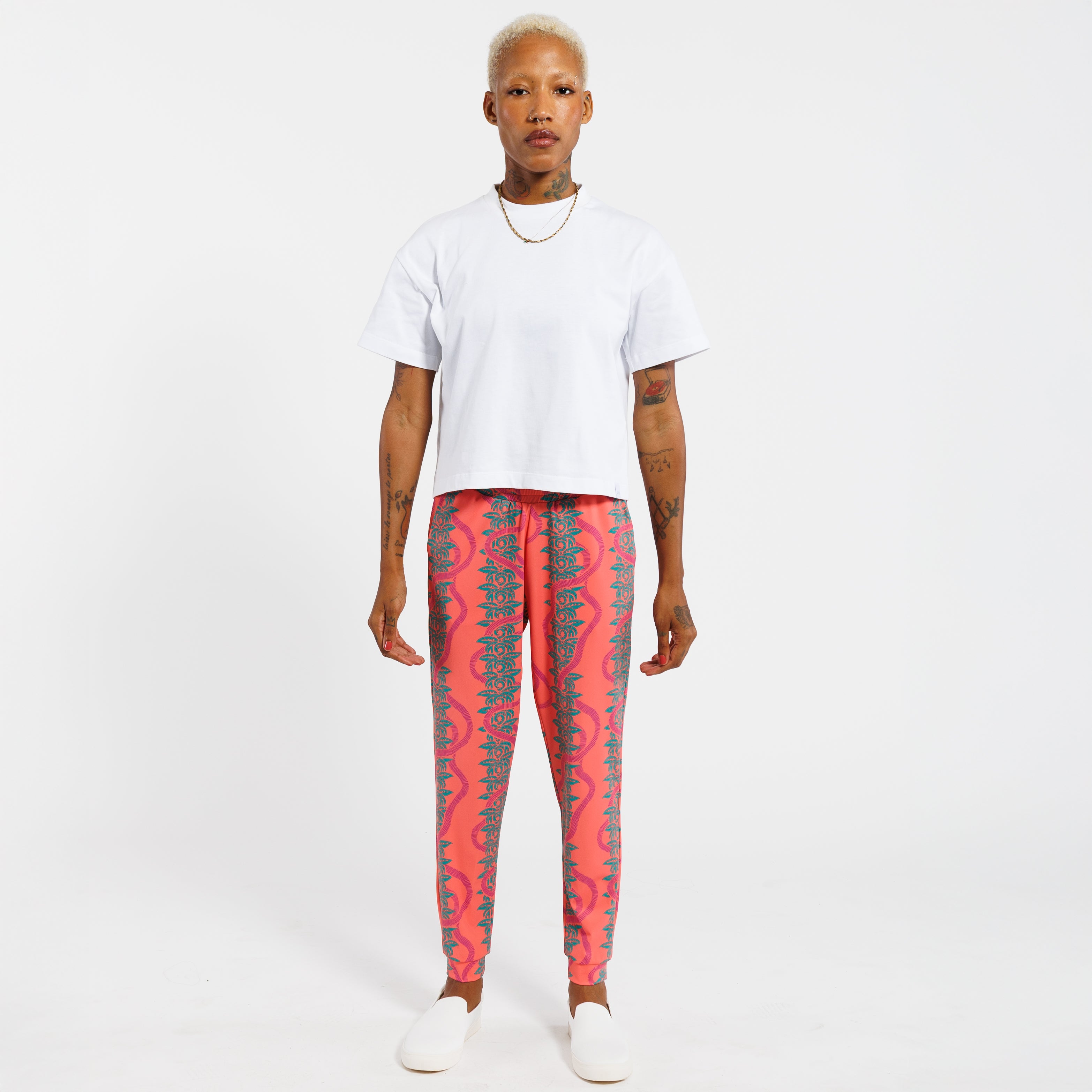 Person wearing a white t-shirt and pink jogger pants with green leaf pattern on a white background