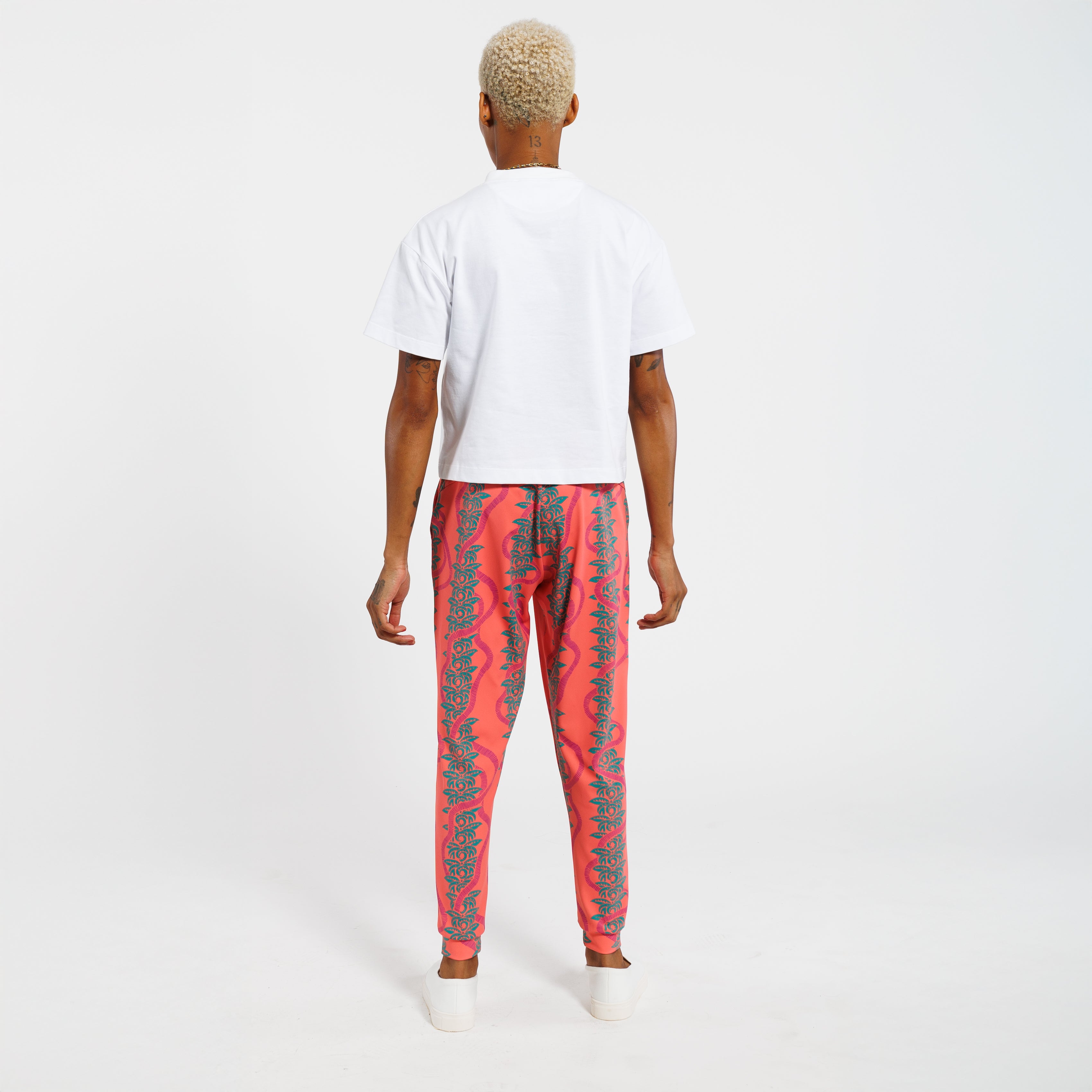 Person wearing a white t-shirt and pink jogger pants with green leaf pattern on a white background