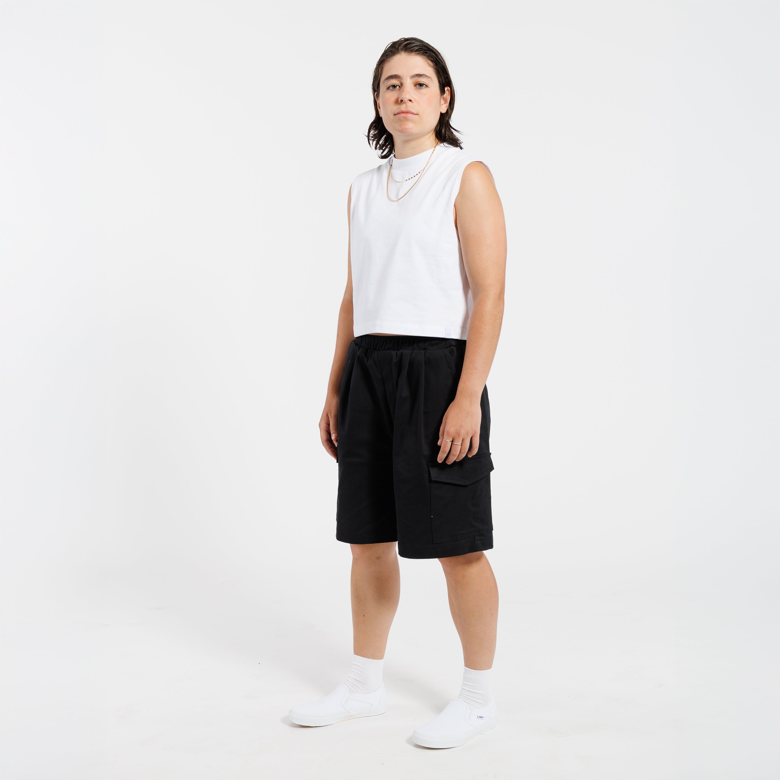 Person wearing a white tank top and black Bermuda shorts on a white background