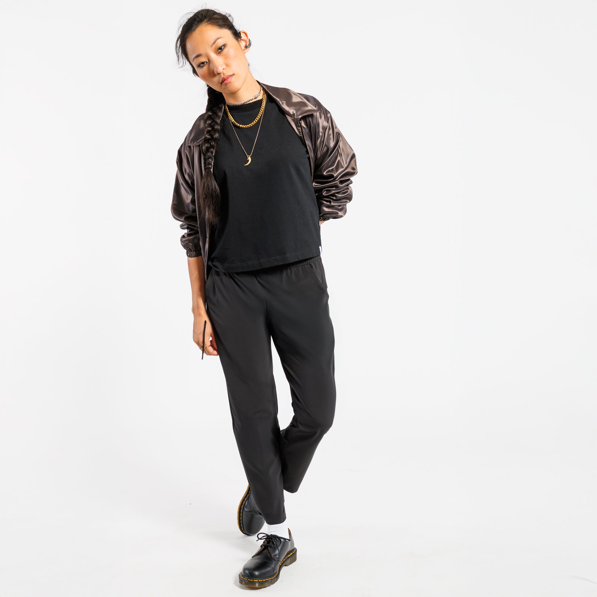 Person wearing a shiny copper jacket and black pants on a white background