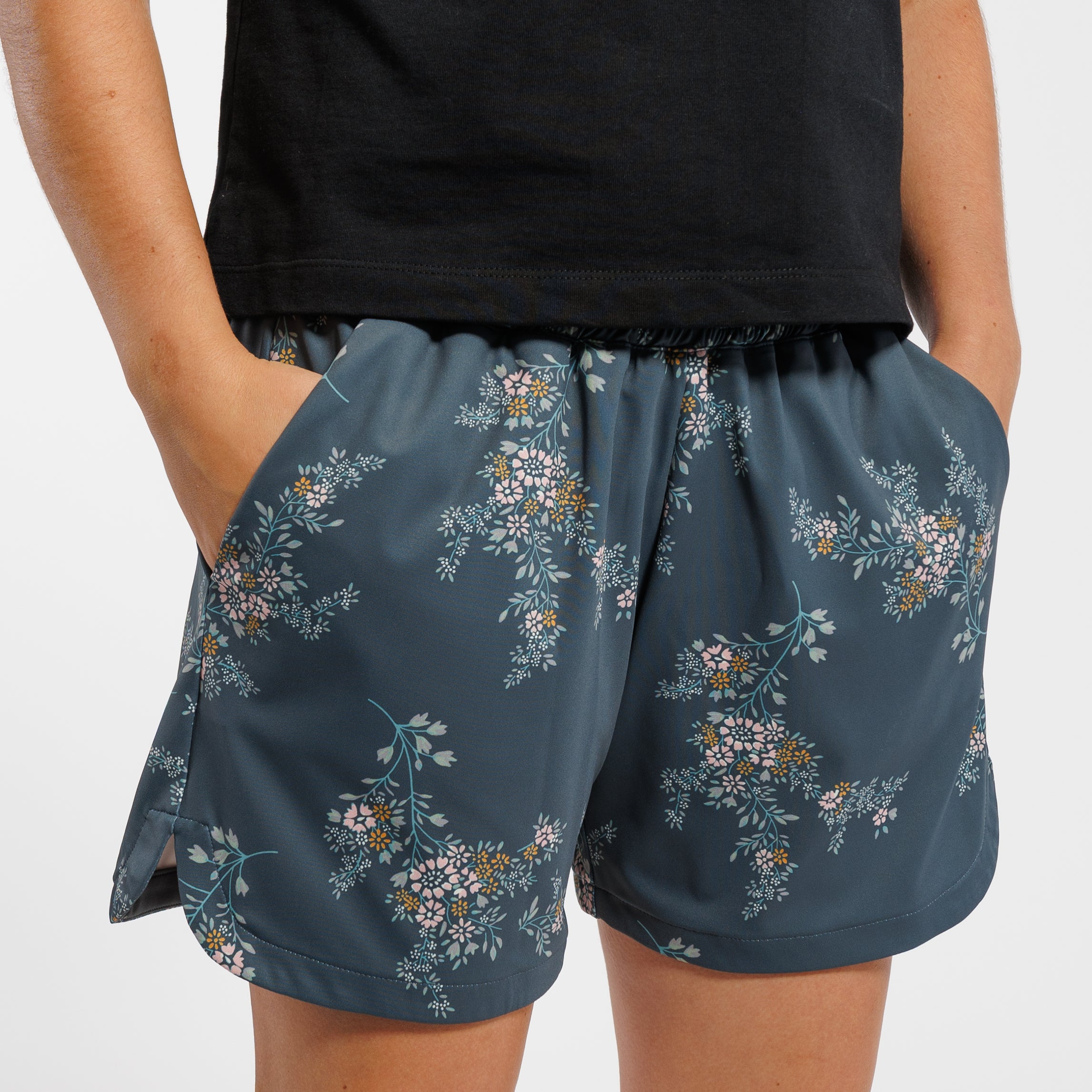Person wearing a black short-sleeve shirt and Floral-patterned shorts on a white background