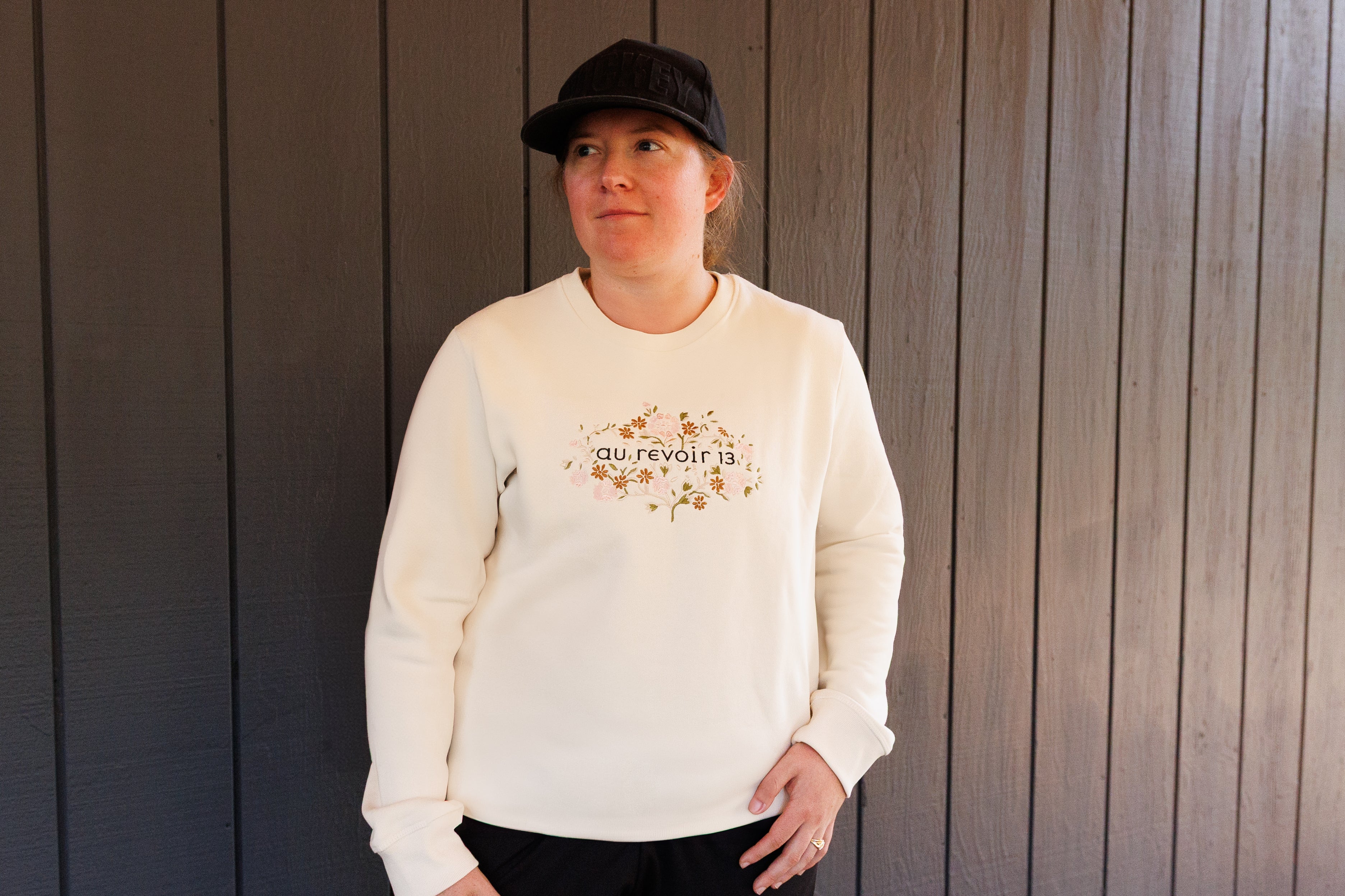 Person wearing a cream sweatshirt with text and graphics against a wooden background
