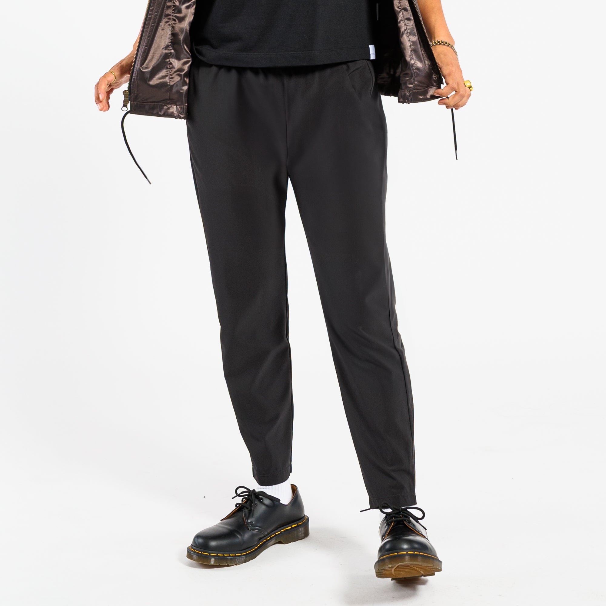 Person wearing black pants and black shoes on a white background