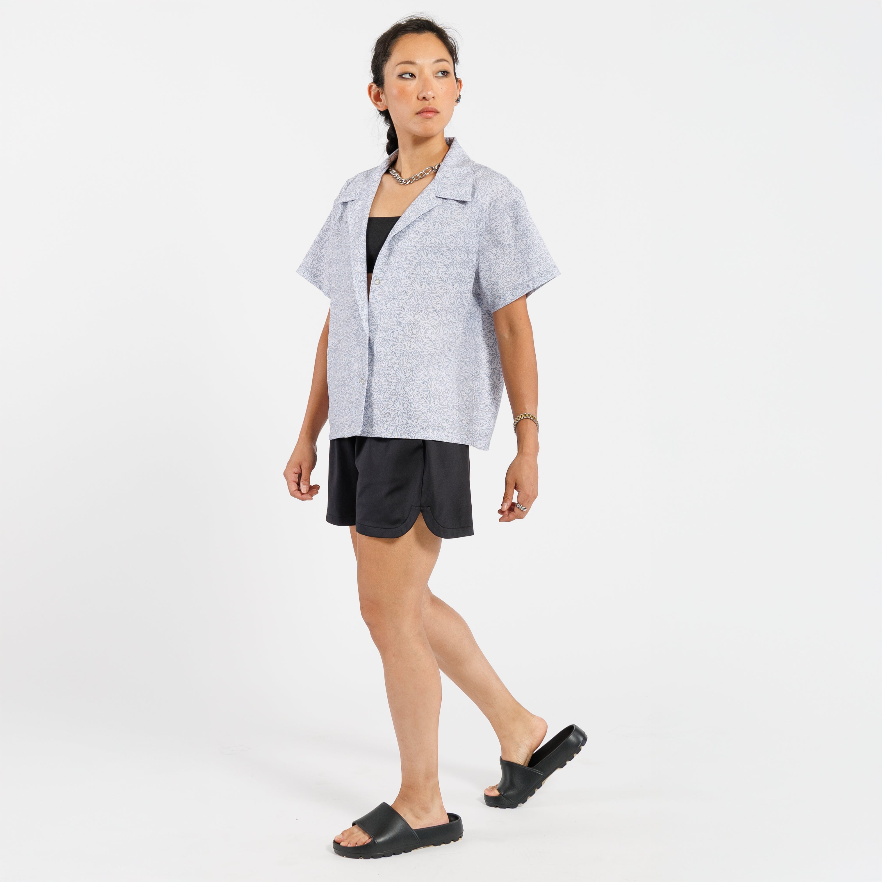 Woman wearing a light gray shirt and black shorts on a white background