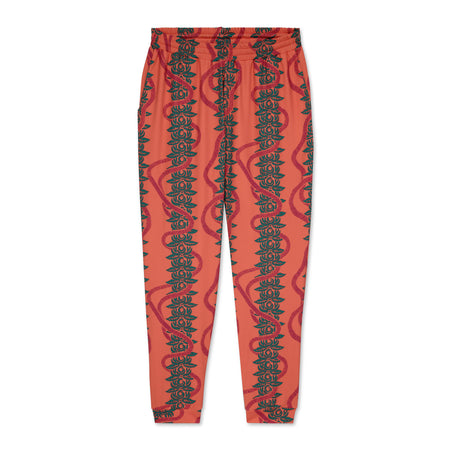 Pink jogger pants with green leaf pattern on a white background