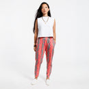 Woman wearing a white cropped tank top and pink patterned with green leaves pants on a white background