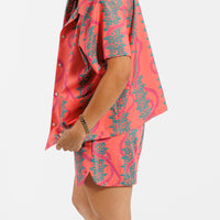 Person wearing a pink and green leaf patterned outfit on a white background.
