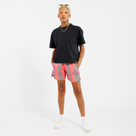 Person wearing a black t-shirt and pink shorts with green leaf pattern on a white background 