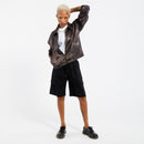 Person wearing a iridescent copper jacket, white shirt, black shorts, and black shoes on a white background