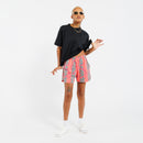 Person wearing a black t-shirt and pink shorts with green leaf pattern on a white background 
