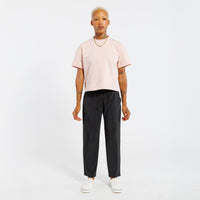 Person wearing a light pink t-shirt and black pants on a white background