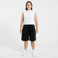 Person wearing a white tank top and black Bermuda shorts on a white background.