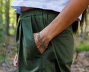 Close-up of olive green Bermuda shorts showing pocket detail with a woman’s hand inside the pocket.