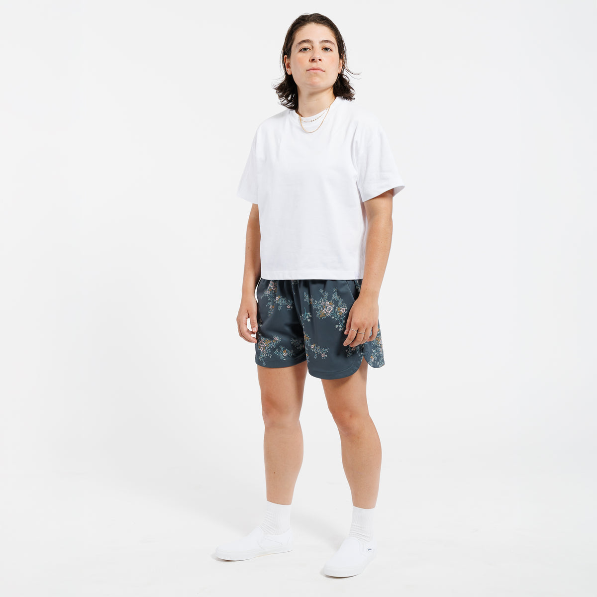 Person wearing a white cropped t-shirt and floral shorts on a white background