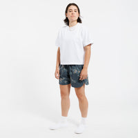 Person wearing a white cropped t-shirt and floral shorts on a white background