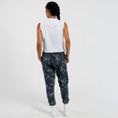 Person wearing a white sleeveless top and dark floral pants on a white background