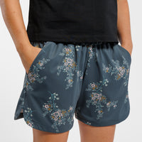 Person wearing a black short-sleeve shirt and Floral-patterned shorts on a white background