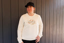 Person wearing a cream sweatshirt with text and graphics against a wooden background