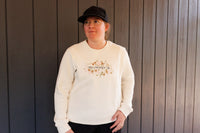 Person wearing a cream sweatshirt with text and graphics against a wooden background