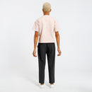 Back view of a person wearing a light pink t-shirt and black pants on a white background