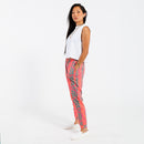 Woman wearing a white cropped tank top and pink patterned with green leaves pants on a white background