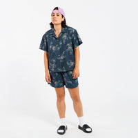 Person wearing a floral shirt and shorts set on a white background