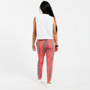 Woman wearing a white cropped tank top and pink patterned with green leaves pants on a white background