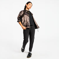 Person wearing a shiny copper jacket and black pants on a white background