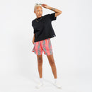 Person wearing a black t-shirt and pink shorts with a green leaves pattern on a white background
