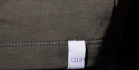 White logo label 'a13' in stitched on gray fabric against jean pant.
